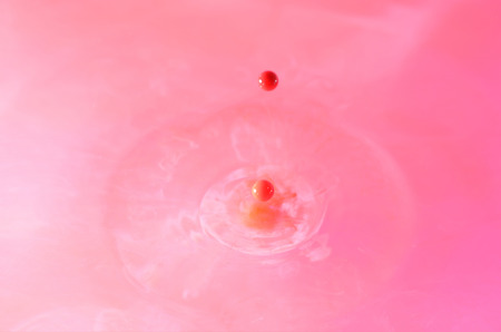 red water drop with ripple on pink backgroundの写真素材