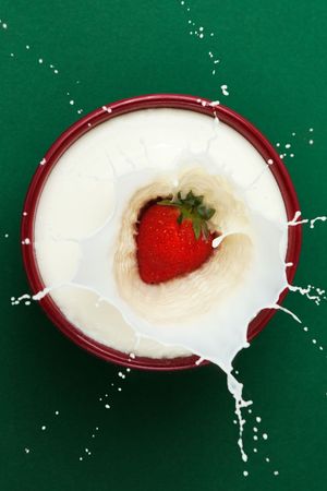 Strawberry dropped into bowl of milk, creating a splash sculptureの写真素材