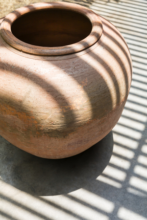The pattern of shadows from the slats on some of clay pot and cement floor