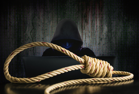 Brown rope noose with computer hacker in black mask and hood in data security, concept of computer danger and online computer system attacksの写真素材