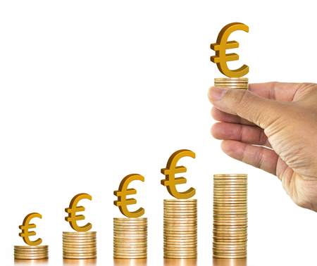 Businesman hand holding golden euro sign on money coin and putting on money coin stack arranged as a graph on white background, concept of money growth and saving moneyの写真素材