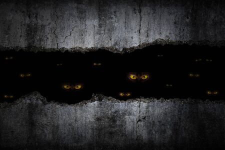 Scary eyes in damaged grungy crack and broken concrete wall and the dark Halloweenの写真素材