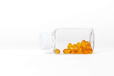 Yellow color fish oil capsules in glass bottle on white backgroundの写真素材