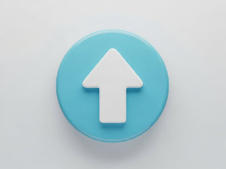 The image features a single, round button with a smooth, light blue surface. On the button, there is a prominent white up arrow positioned in the center. The button is set against a plain, light gray background, which contrasts with the blue and white colors of the button. The overall composition is simple and clean, emphasizing the button and its arrow.の素材