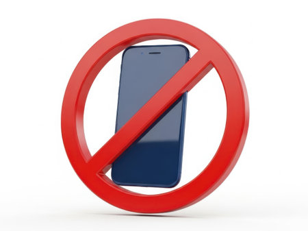 The image depicts a smartphone positioned centrally, with a prominent red prohibition symbol superimposed over it. The prohibition symbol, a red circle with a diagonal line, indicates that the use of the smartphone is not allowed. The smartphone appears to be a modern, sleek device with a dark screen, and the background is a plain white, which emphasizes the boldness of the red symbol and the smartphone.の素材