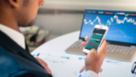 Businessman analyzing investment charts with mobile phone in office. blur background