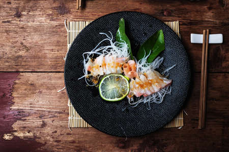 Sea Bream sashimi marinated with ginger, lemon, mirin, wasabi and soy sauce. Garnished by radish and lime leaf.の写真素材