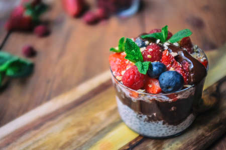 Breakfast for the spring time; Over night vanilla chia seeds pudding in Almond milk top with fresh strawberry, raspberry and blue berry. Garnished by mint leave and granola.の写真素材