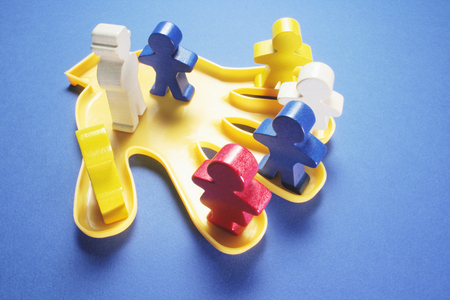 Plastic Hand with Wooden Figures on Blue Backgroundの写真素材