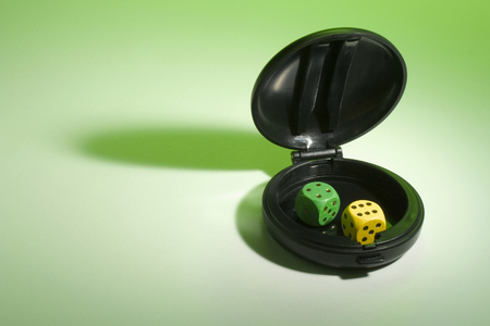 Dice in Compact Case on Green Backgroundの写真素材