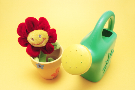 Toy Sunflower and Watering Can with Yellow Backgroundの写真素材