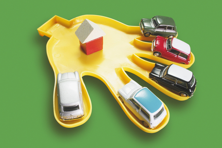 Plastic Hand with Toy Cars on Green Backgroundの写真素材