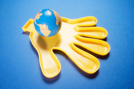 Globe on Plastic Hand with Blue Backgroundの写真素材