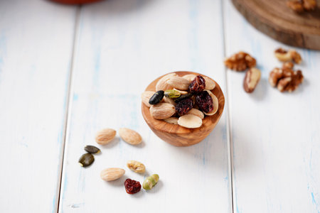 Various of berries, nuts and seeds in wooden bowl on a light wooden table.の写真素材