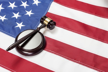 Wooden judge gavel and soundboard laying over US flagの写真素材