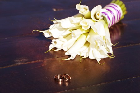 a wedding rings and a bouquet of white liliesの写真素材