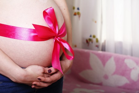pregnant young girl belly close-up, in anticipation of a new lifeの写真素材