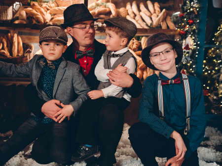 Happy father with his sons on New Years Eve in festive New Years decorations. Stylishly dressed family in retro vintage clothing for the new year.の写真素材