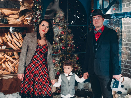 Beautifully dressed in retro style parents with their little son on the eve of New Years holidays. Festive Christmas vintage happy family atmosphere.の写真素材