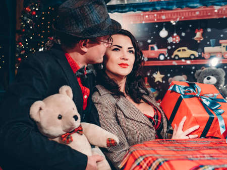 A beautiful couple in love dressed in retro style sits at a table in beautiful New Years decorations.の写真素材