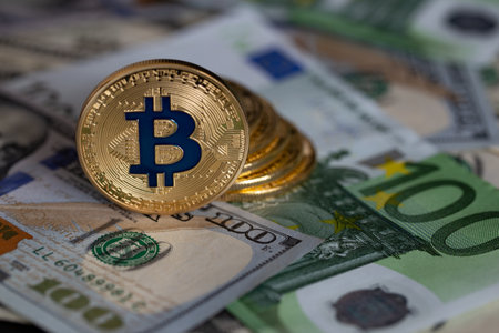 Bitcoins close-up on the background of paper bills of different countries.