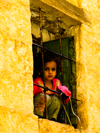 Girl looking to the street behind window, - 04-11-2009 Mahwit. Yemenのeditorial素材