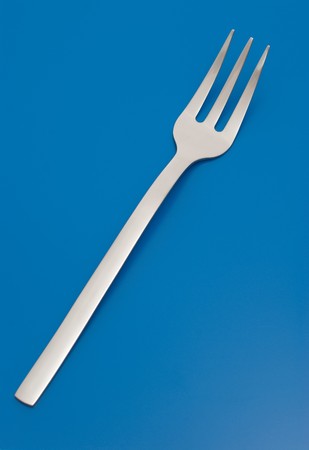Fork for meat carving isolated on the blue background.の写真素材