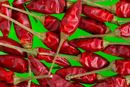 Macro view of red chilli peppers on green background.