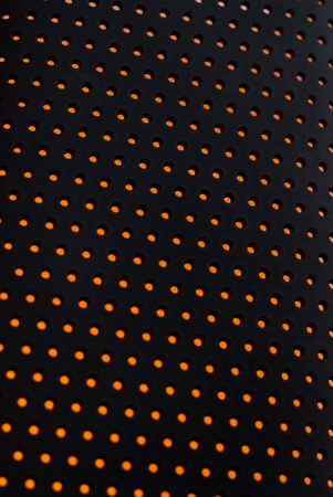 Black plastic mesh texture backlit with orange light.の写真素材