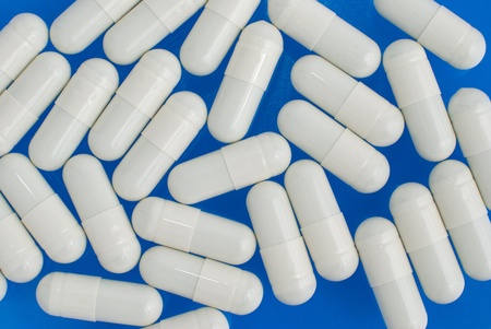 Macro view of white pills on blue background.