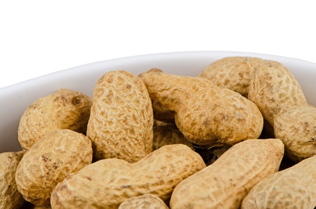 Macro shot of peanuts in a ceramic container on white background.の写真素材