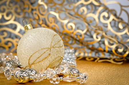 Golden christmas ball with decorations on golden surface and blured backdrop.の写真素材