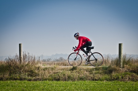 Man on road bike riding down open country road.の写真素材
