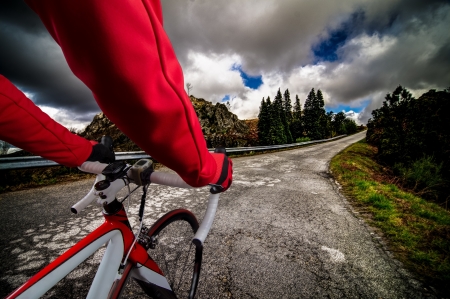 Cyclist on road bike through a asphalt road in the mountains and blue sky with clouds.の写真素材