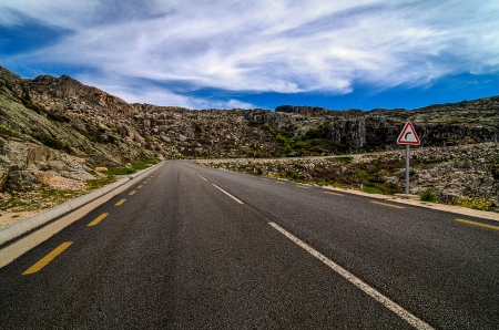 Asphalt road in the mountains and blue sky with clouds.の写真素材