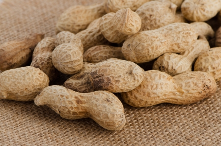 Peanuts on brown textile background.