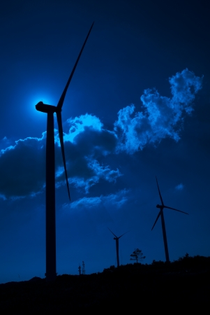 Wind turbine in the back light of the moon with blue sky and clouds.の写真素材