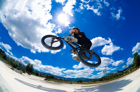 BMX rider jumps while doing cross bar trick. BMX rider jumps while doing cross bar trick.