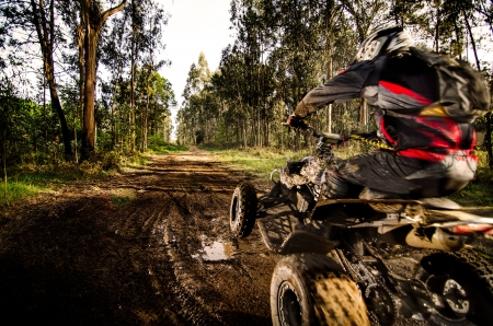 Quad rider jumping on a muddy forest trail.の写真素材