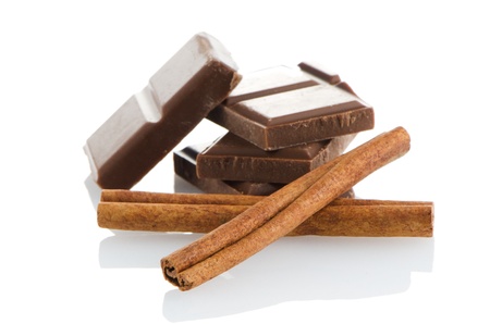 Chocolate parts and cinnamon sticks isolated on white background.の写真素材
