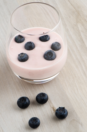 Yogurt with fresh blueberries on a wooden table set.の写真素材