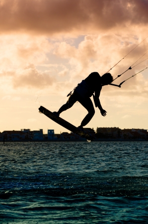 Silhouette of a kitesurfer flying above the water at sunsetの写真素材
