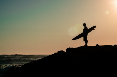 A surfer watching the waves at sunset in Portugal.の写真素材