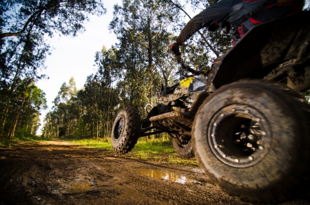 Quad rider jumping on a muddy forest trail.の写真素材