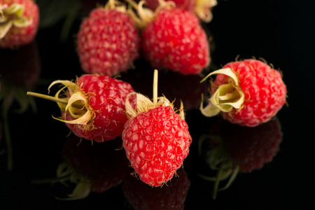 Fresh raspberries on black reflective background.の写真素材
