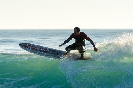Long boarder surfing the waves at sunset in Portugal.の写真素材