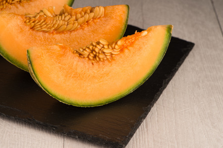 Juicy honeydew melon on a black slate tray.の写真素材