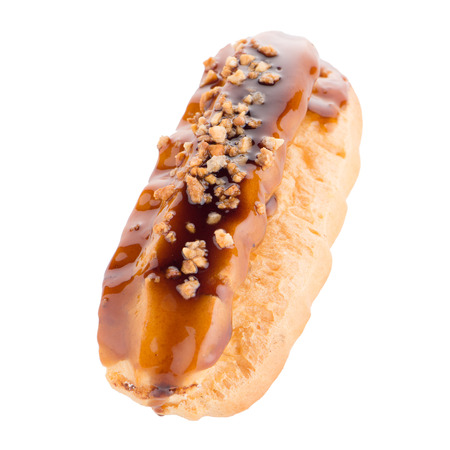 Eclair with caramel decoration on white reflective background.