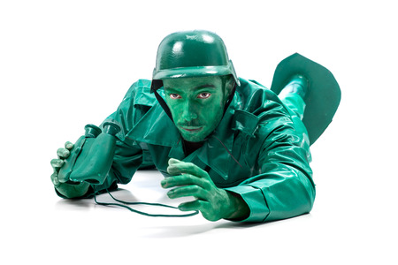 Man on a green toy soldier costume, crawling with binocolous isolated on white background.の写真素材