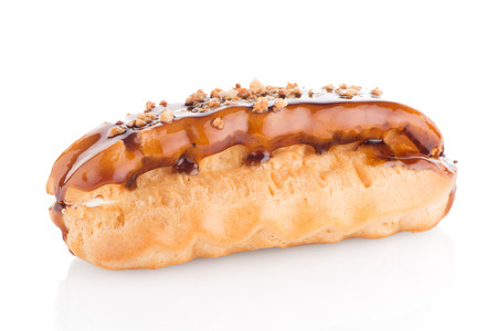 Eclair with caramel decoration on white reflective background.の写真素材